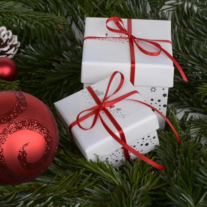 Wrapped gifts and red ornaments on fir branches.