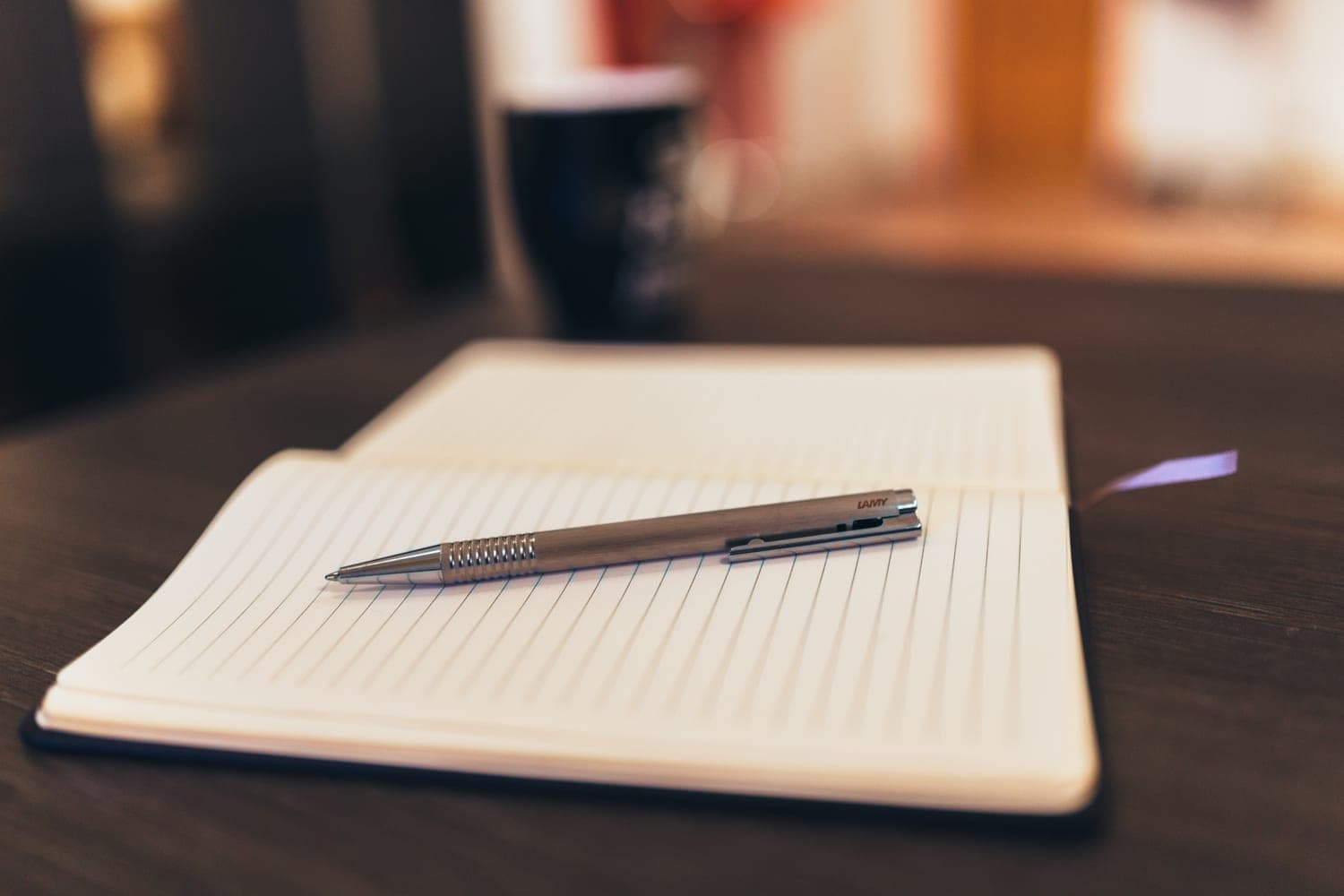 An open notebook and a silver pen on a table.